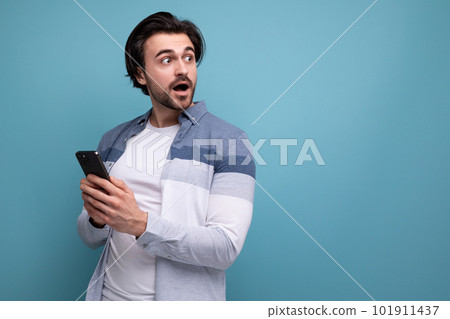 happy joyful brunette guy in casual style with a smartphone in his hands 101911437