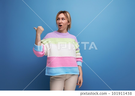 cute blond woman in casual look surprised showing wall with copy space on blue background cute blond woman in casual look surprised showing wall with copy space on blue background 101911438