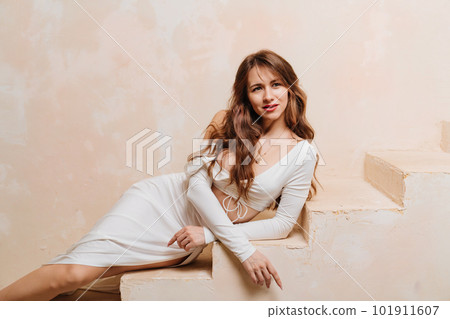 a beautiful woman in a white sexy torus with neckline and skirt on the steps a beautiful woman in a white sexy torus with neckline and skirt on the steps 101911607