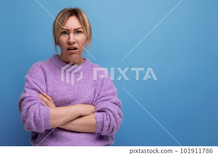 doubting blond woman looking contemptuously at camera on blue background with copy space doubting blond woman looking contemptuously at camera on blue background with copy space 101911786