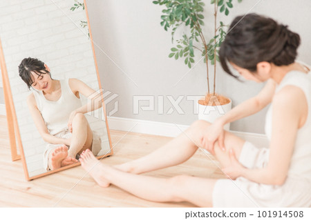 一個微笑的日本女人在家裡做大腿按摩以防止水腫 一個微笑的日本女人在家裡做大腿按摩以防止水腫 101914508