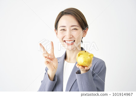 Business woman holding a piggy bank and making a peace sign White background 101914967