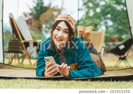 Young Asian female camper using smartphone in autumn winter camping outdoors Young Asian female camper using smartphone in autumn winter camping outdoors 101915350