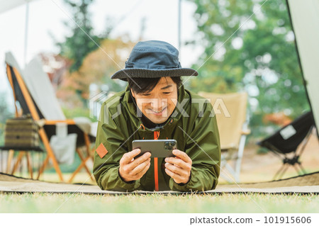 Young asian male camper using smartphone in autumn winter camping outdoors 101915606