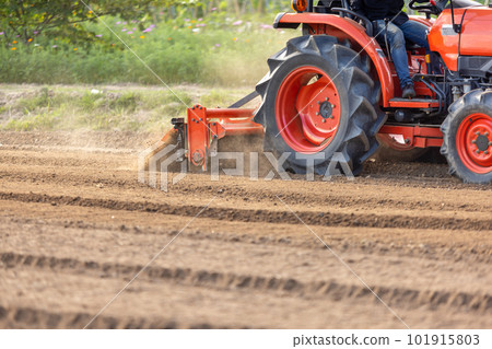 Tractor cultivating land with a rotary tiller in farm. 101915803
