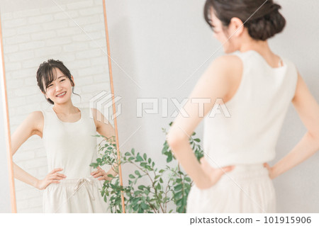 Smiling Asian woman checking her figure and style in the mirror 101915906