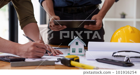 Architect and Engineer working with blueprints for architectural plan, engineer sketching a construction project, green energy concept 101916254