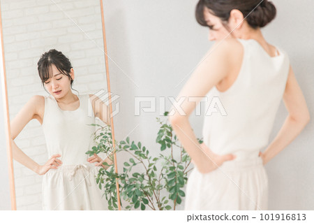 Asian woman suffering from anorexia and weight loss looking at the mirror and checking her waist 101916813