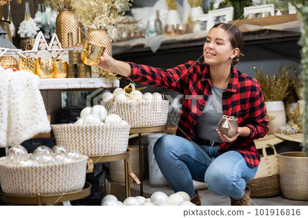 Positive woman chooses Christmas gifts in gift shop Positive woman chooses Christmas gifts in gift shop 101916816