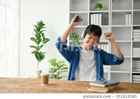 Happy young college student enjoy himself, listening to music while taking a break 101918580