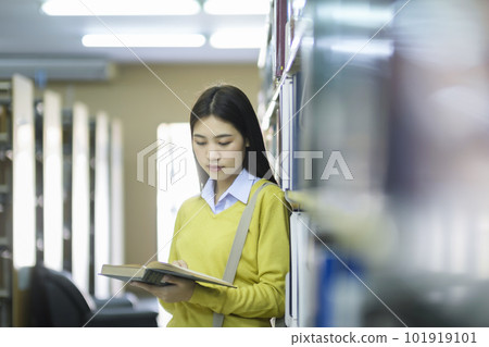 Student standing and reading book at library. Student standing and reading book at library. 101919101