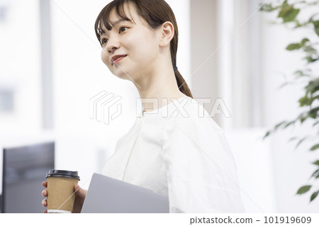 Young woman holding a computer and a paper cup in the office Business image 101919609