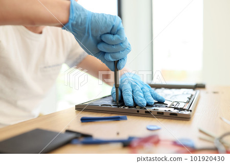 Male master in rubber gloves unscrews printed circuit board 101920430