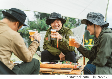 Asian camper toasting with beer at campsite with male friends Asian camper toasting with beer at campsite with male friends 101922578