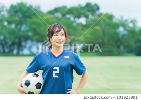 A Japanese woman who is a fan supporter playing soccer with a smile while holding a soccer ball 101923991
