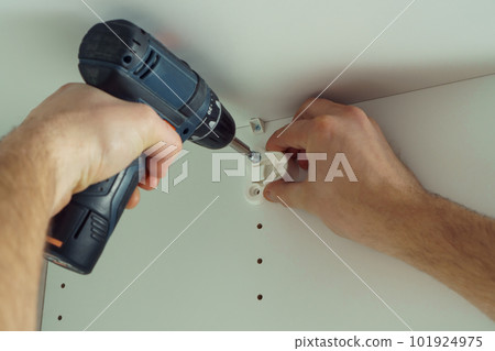 Male hands screw in to insert plastic support into one of series of holes to fix white hanger bar. Holds screwdriver. 101924975