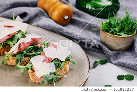Bruschetta with beef, arugula and parmesan cheese Bruschetta with beef, arugula and parmesan cheese 101925237