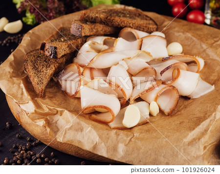 Ukrainian traditional food - sliced smoked lard on cutting board with garlic 101926024