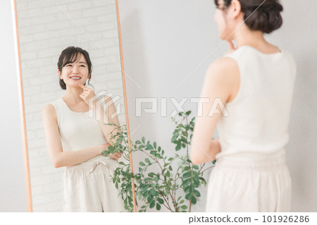 Young Asian woman with teeth whitening and orthodontics looking in the mirror Young Asian woman with teeth whitening and orthodontics looking in the mirror 101926286