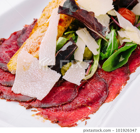 Beef carpaccio with salad and Parmesan on a white plate 101926347