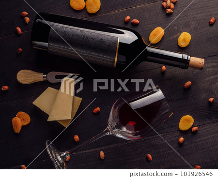 Glass and bottle of red wine with cheese, dried apricots and nuts Glass and bottle of red wine with cheese, dried apricots and nuts 101926546