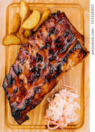 Pork loin ribs served on chopping board and potato wedges 101926807