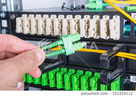 Hand of computer technician connecting fiber optics cable into data switch Hand of computer technician connecting fiber optics cable into data switch 101928112