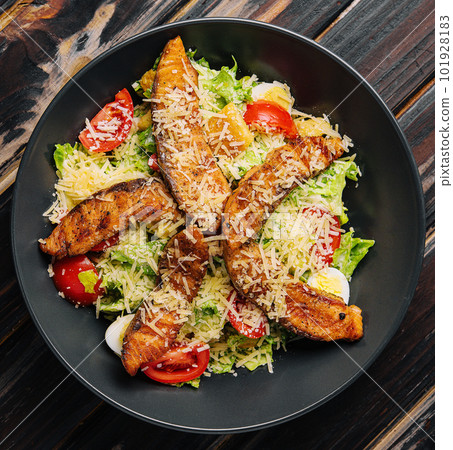 Delicious fresh salad with red fish on wooden table Delicious fresh salad with red fish on wooden table 101928183