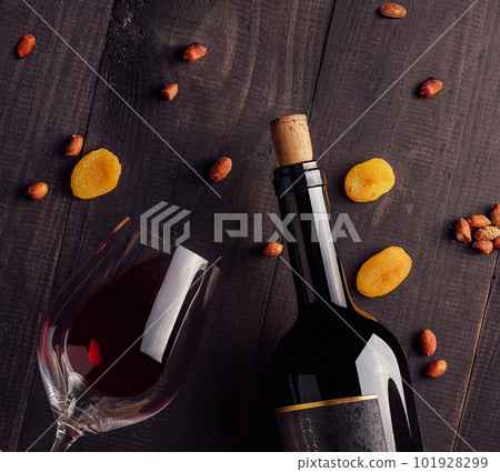 Glass and bottle of red wine with cheese, dried apricots and nuts Glass and bottle of red wine with cheese, dried apricots and nuts 101928299