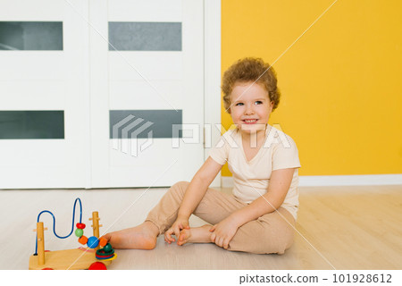 Four-year-old boy sits on the floor and plays with toys at home or in kindergarten Four-year-old boy sits on the floor and plays with toys at home or in kindergarten 101928612