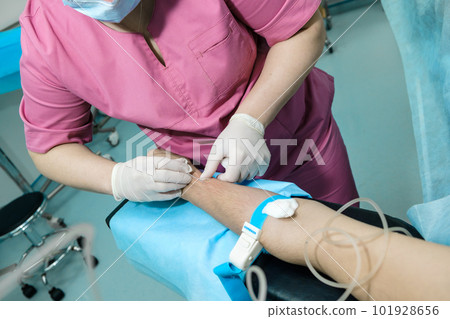 The doctor inserts a dropper needle into the patient's arm. 101928656