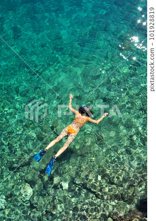Woman snorkeling in the sea in orange bikini Woman snorkeling in the sea in orange bikini 101928819