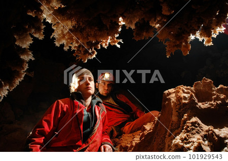 Spelunkers admiring stalactites in a cave Spelunkers admiring stalactites in a cave 101929543