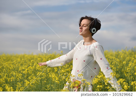 Young, emotional and happy woman listening music in headphones in a canola field 101929662