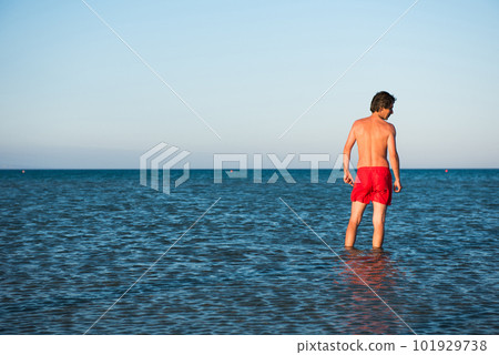 Slim guy posing in red swimwear in sea water 101929738