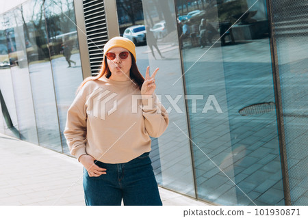Portrait of a happy young woman in yellow hat and pink sunglasses with peace sign outdoors. Urban lifestyle concept. Traveler Portrait of a happy young woman in yellow hat and pink sunglasses with peace sign outdoors. Urban lifestyle concept. Traveler 101930871