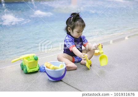 Asian baby girl playing with water toys by the pool. 101931676