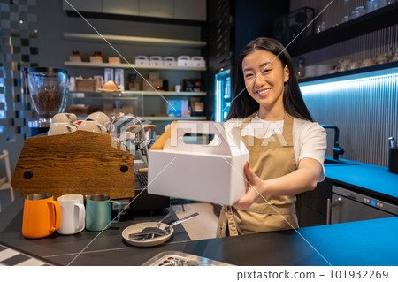 Joyful coffeehouse employee with a packaged takeout meal 101932269