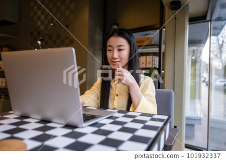 Concentrated female remote employee using the laptop in a coffeehouse 101932337