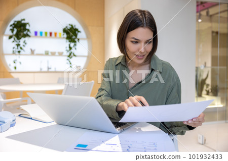 Concentrated female office worker dealing with paperwork Concentrated female office worker dealing with paperwork 101932433