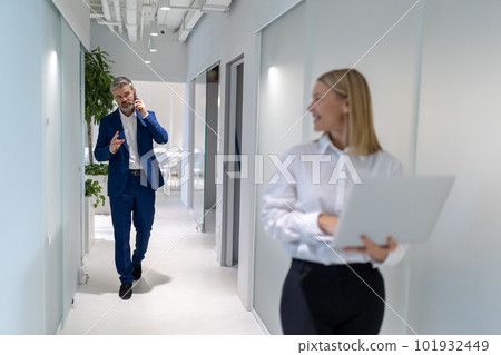Confident businessman approaching his female colleague during the phone call Confident businessman approaching his female colleague during the phone call 101932449