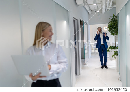 Joyous entrepreneur approaching his business partner during the phone call Joyous entrepreneur approaching his business partner during the phone call 101932450