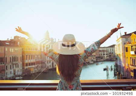 Seen from behind young solo traveller woman in floral dress Seen from behind young solo traveller woman in floral dress 101932498