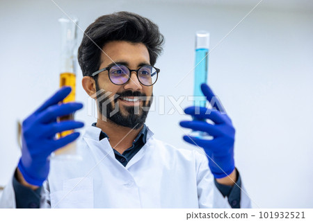 Scientist examining liquid in test tube in laboratory, researcher wearing lab coat and rubber gloves 101932521