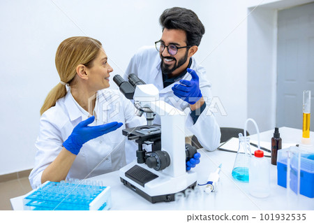 Male scientist working with microscope, doctor's team in laboratory doing research. 101932535