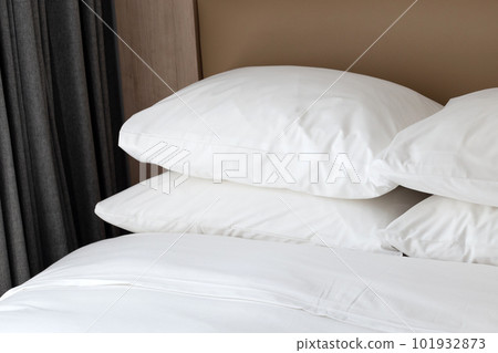 Bed with white pillows in bedroom 101932873