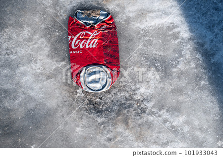 SHYMKENT, KAZAKHSAN - JANUARY 21, 2023: crumpled can of Coca Cola lies on the snow 101933043
