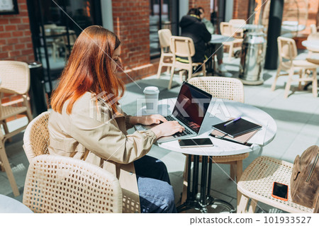 Young woman enjoying a coffee, 30s girl with laptop sitting on the cafe terrace on the modern city street. Traveler, Online education, urban, working or shopping concept Young woman enjoying a coffee, 30s girl with laptop sitting on the cafe terrace on the modern city street. Traveler, Online education, urban, working or shopping concept 101933527