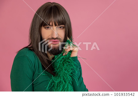 Handsome confident transgender with makeup and wig wearing green feather dress looking at camera 101933542