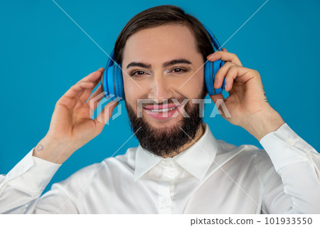 Happy cheerful transgender man listening favorite songs on headphones looking at camera with smile 101933550